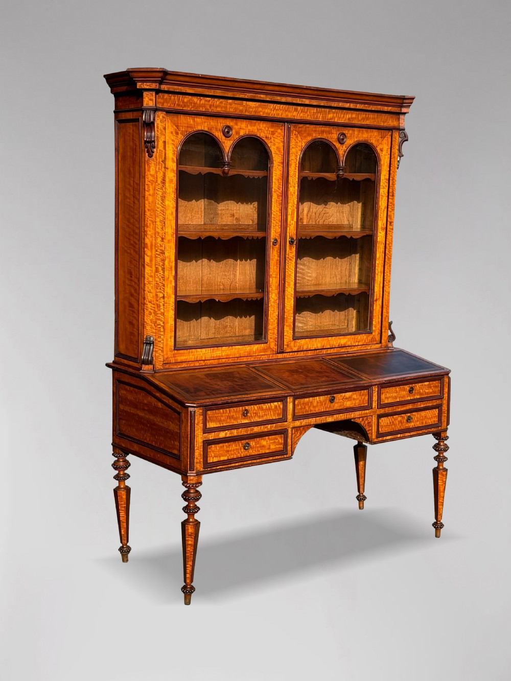 A 19th-century French maple bureau bookcase featuring a top glazed two-door display section above a kneehole writing desk with leather inset panels and turned legs. View II