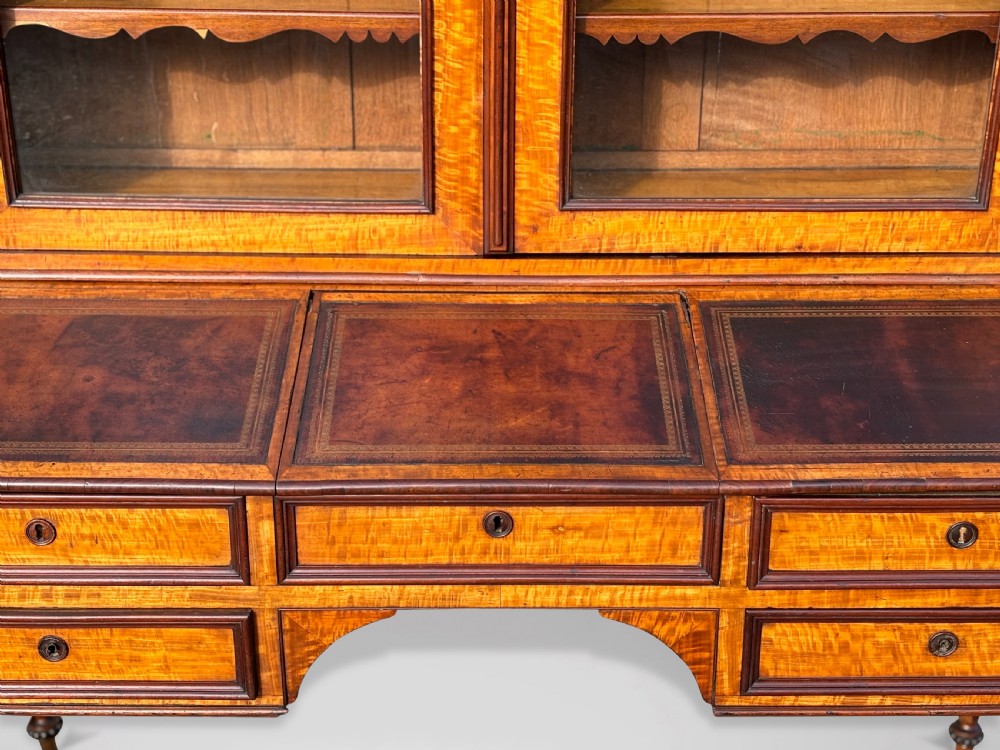 A 19th-century French maple bureau bookcase featuring a top glazed two-door display section above a kneehole writing desk with leather inset panels and turned legs. View VI