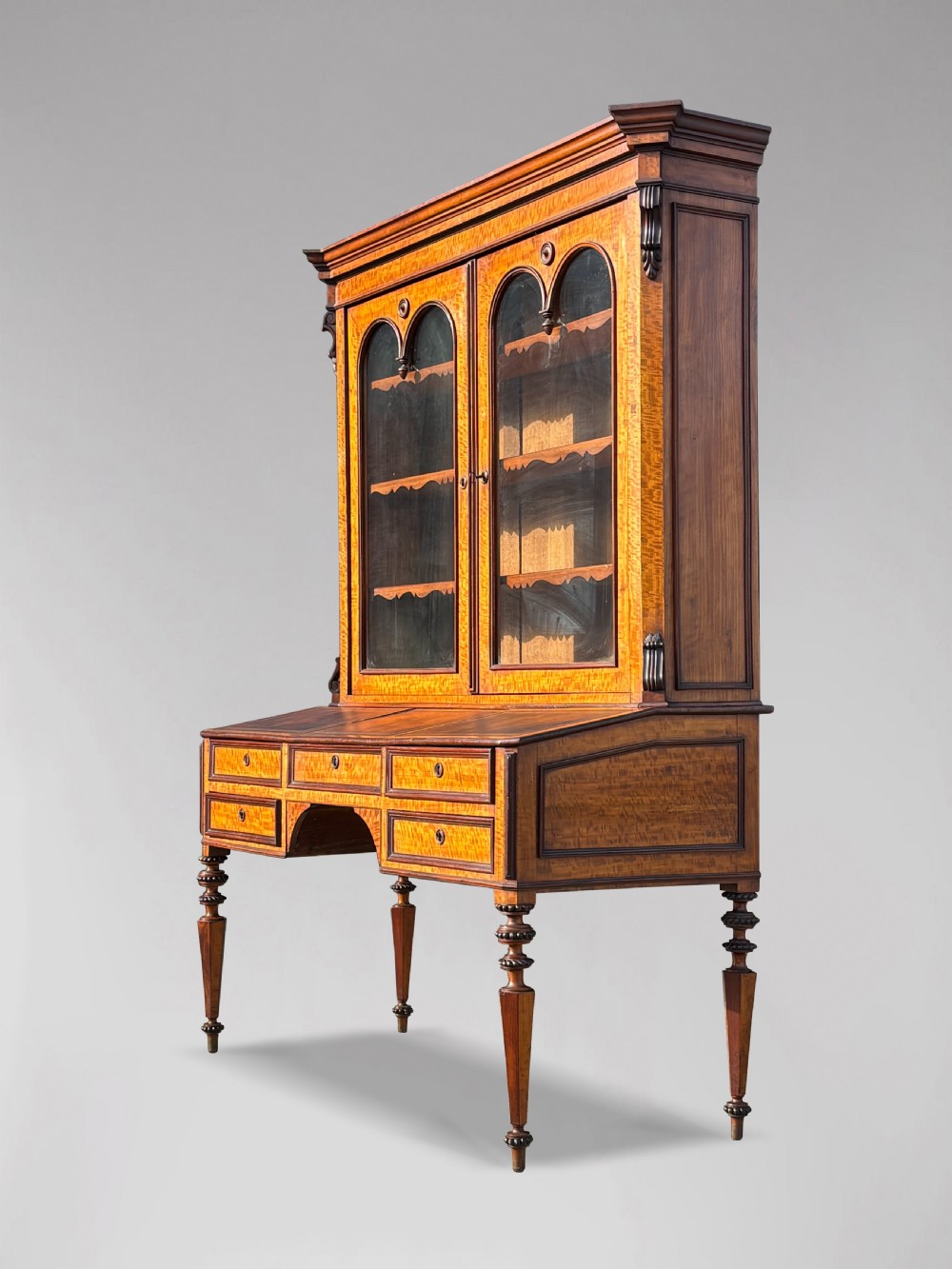A 19th-century French maple bureau bookcase featuring a top glazed two-door display section above a kneehole writing desk with leather inset panels and turned legs. View IX