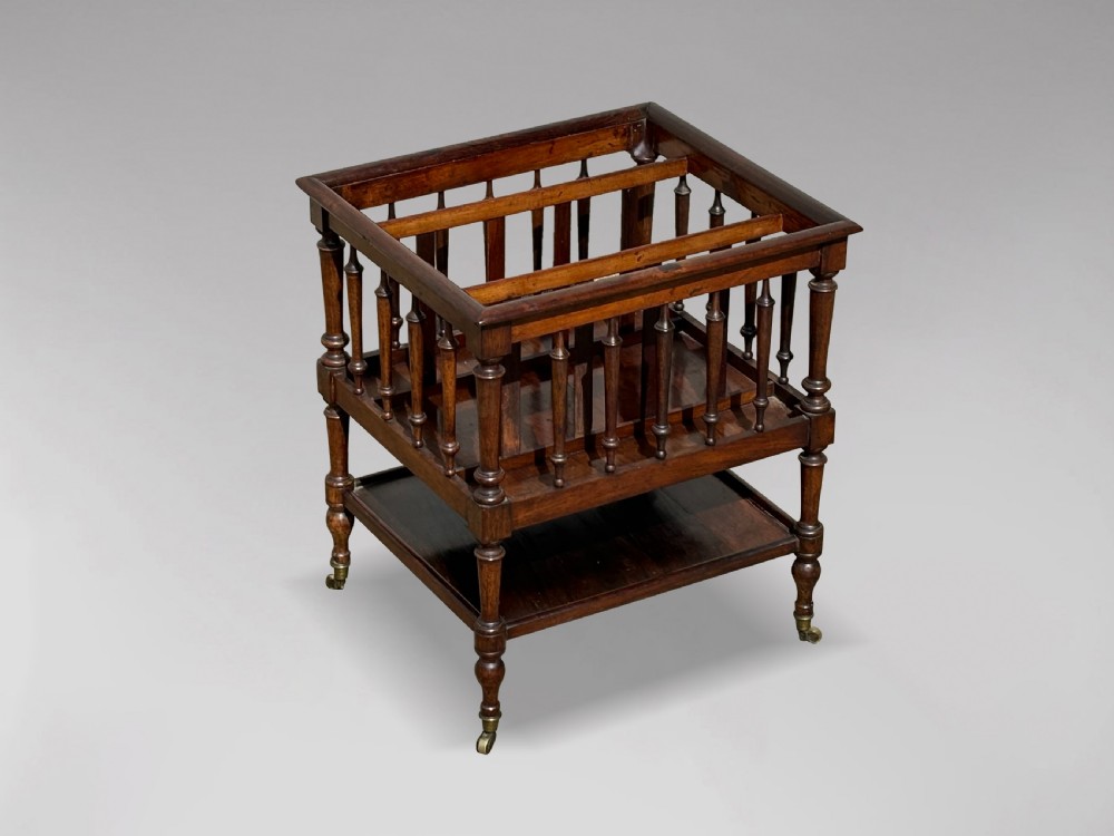 A nineteenth-century dark rosewood canterbury featuring turned spindle supports, divided upper compartments, a lower open shelf, and brass castors. View VII
