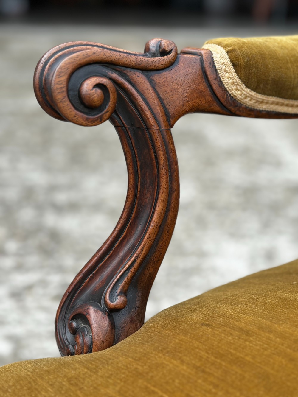 A 19th-century Victorian mahogany armchair upholstered in tufted olive green velvet with carved scroll arms and cabriole legs on brass castors. View V