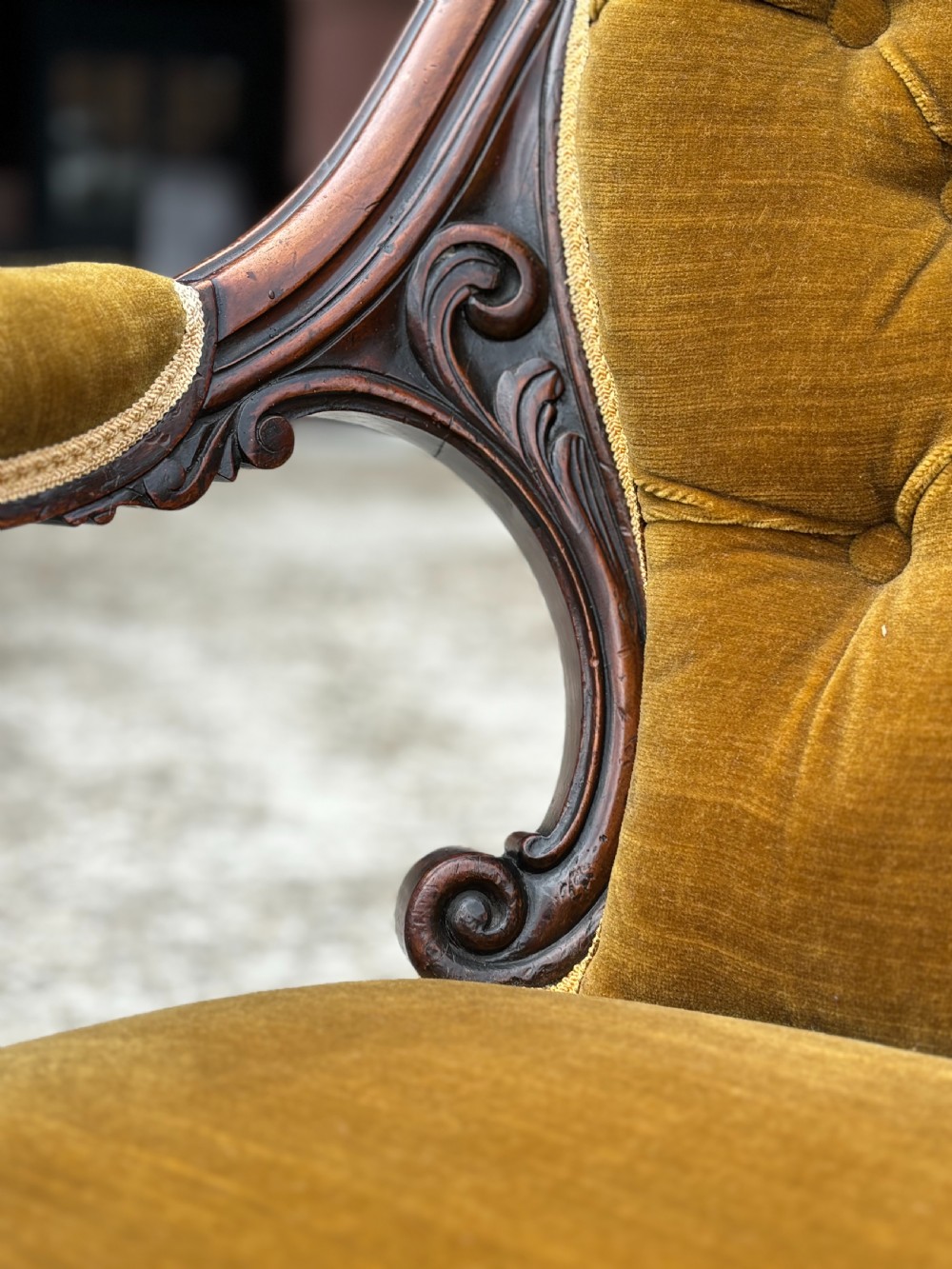 A 19th-century Victorian mahogany armchair upholstered in tufted olive green velvet with carved scroll arms and cabriole legs on brass castors. View VI