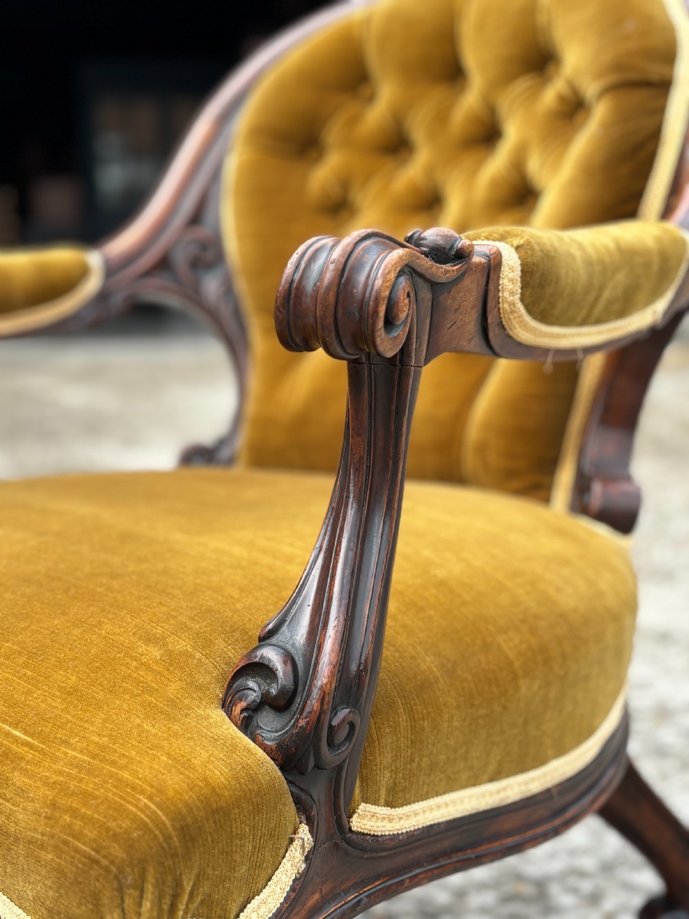 A 19th-century Victorian mahogany armchair upholstered in tufted olive green velvet with carved scroll arms and cabriole legs on brass castors. View VII