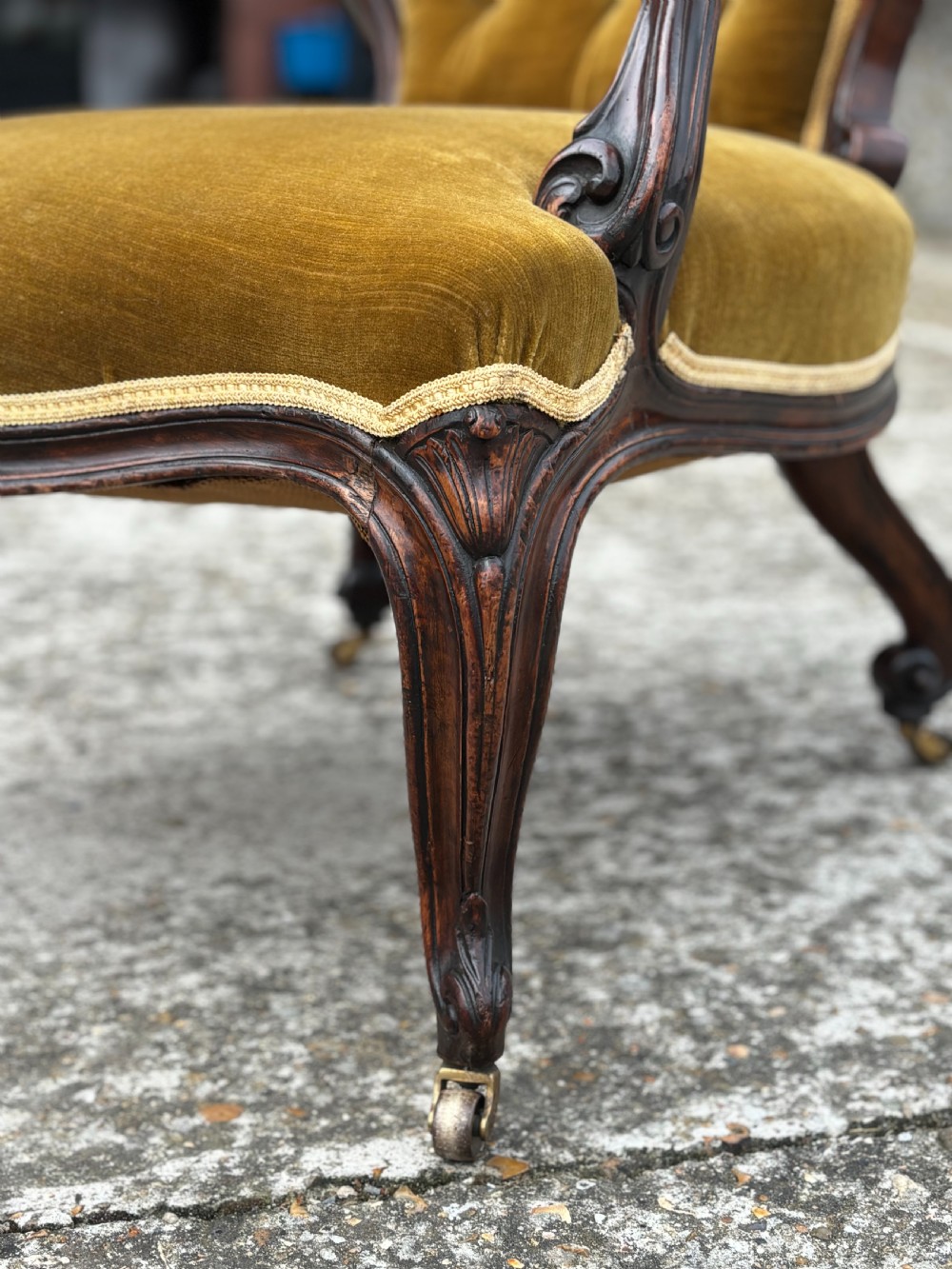 A 19th-century Victorian mahogany armchair upholstered in tufted olive green velvet with carved scroll arms and cabriole legs on brass castors. View VIII