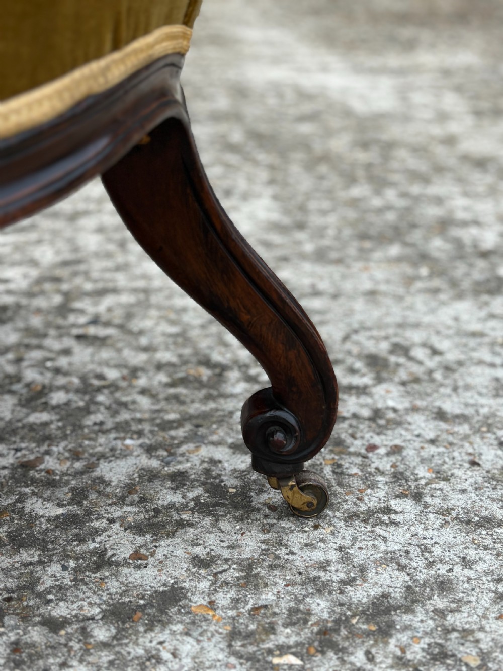 A 19th-century Victorian mahogany armchair upholstered in tufted olive green velvet with carved scroll arms and cabriole legs on brass castors. View IX