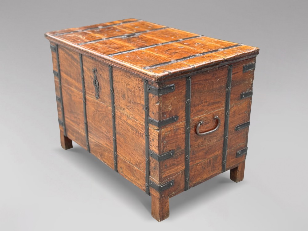 A nineteenth-century Anglo-Indian teak storage trunk featuring heavy iron banding, iron side carrying handles, and an aged timber patina. View III