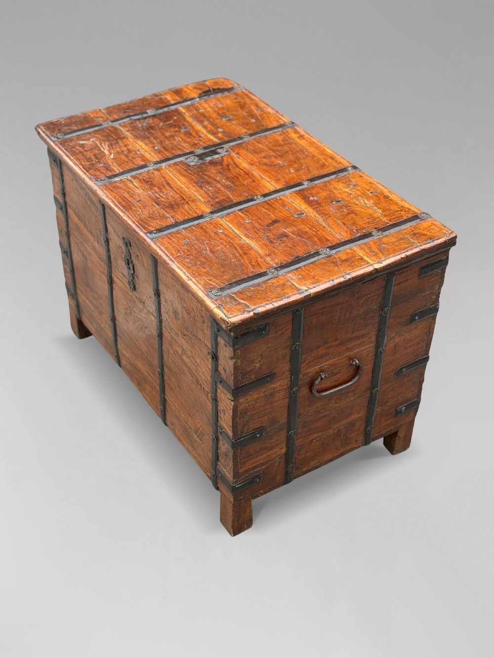 A nineteenth-century Anglo-Indian teak storage trunk featuring heavy iron banding, iron side carrying handles, and an aged timber patina. View VI
