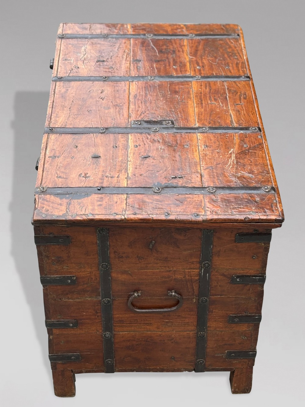 A nineteenth-century Anglo-Indian teak storage trunk featuring heavy iron banding, iron side carrying handles, and an aged timber patina. View VII