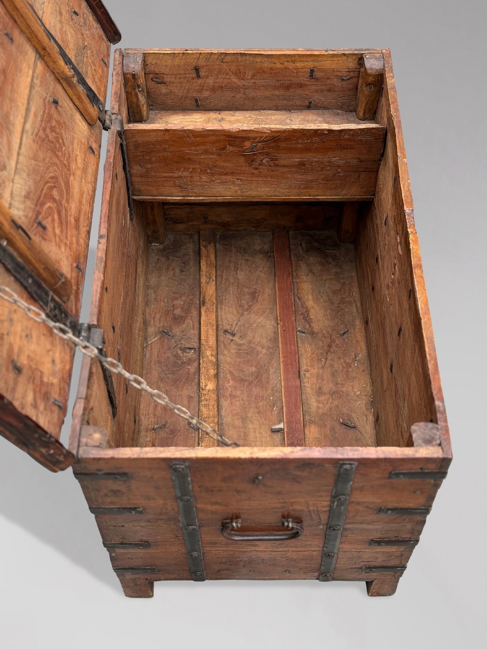 A nineteenth-century Anglo-Indian teak storage trunk featuring heavy iron banding, iron side carrying handles, and an aged timber patina. View VIII