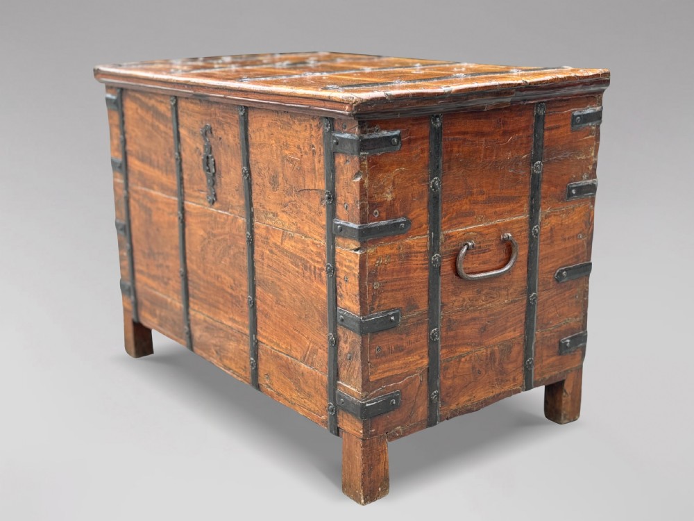 A nineteenth-century Anglo-Indian teak storage trunk featuring heavy iron banding, iron side carrying handles, and an aged timber patina. View X