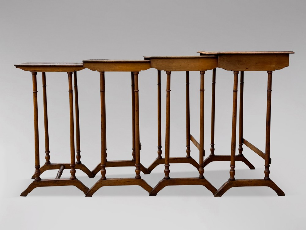 A set of four graduating French walnut nesting tables featuring geometric parquetry tops, central floral marquetry inlays, turned legs, and trestle feet. View VI