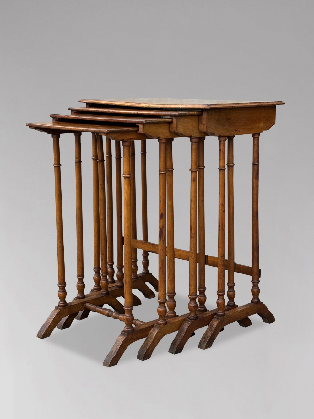 A set of four graduating French walnut nesting tables featuring geometric parquetry tops, central floral marquetry inlays, turned legs, and trestle feet. View VII