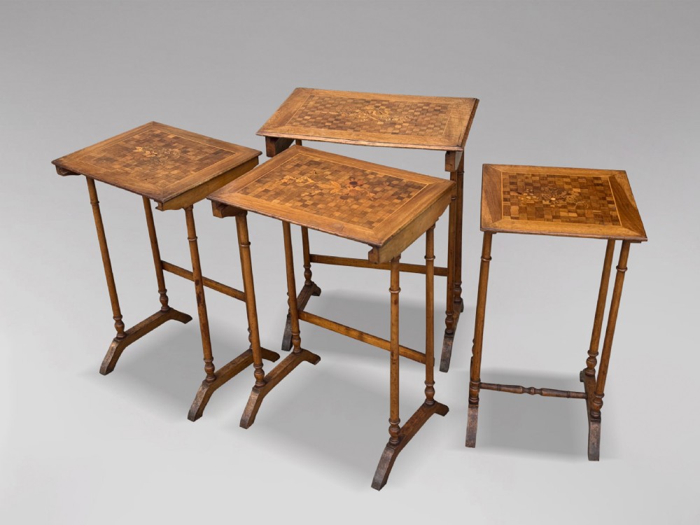 A set of four graduating French walnut nesting tables featuring geometric parquetry tops, central floral marquetry inlays, turned legs, and trestle feet. View IX