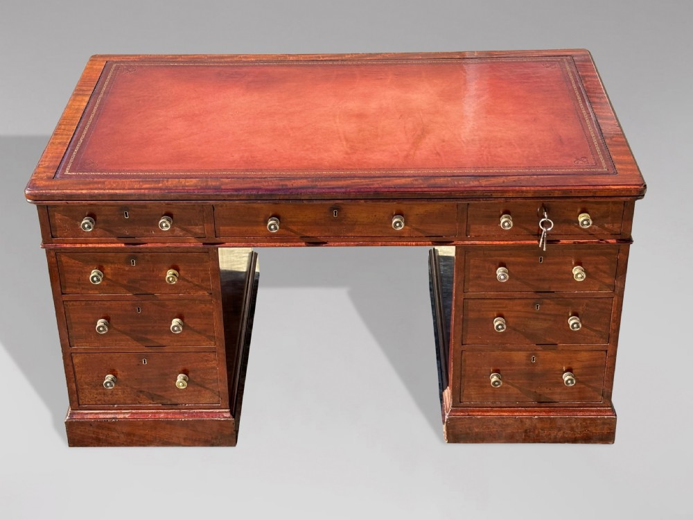 A Victorian flame mahogany partners desk featuring a brown leather inset writing surface, multiple drawers with brass knob handles on twin pedestals, resting on plinth bases. View II