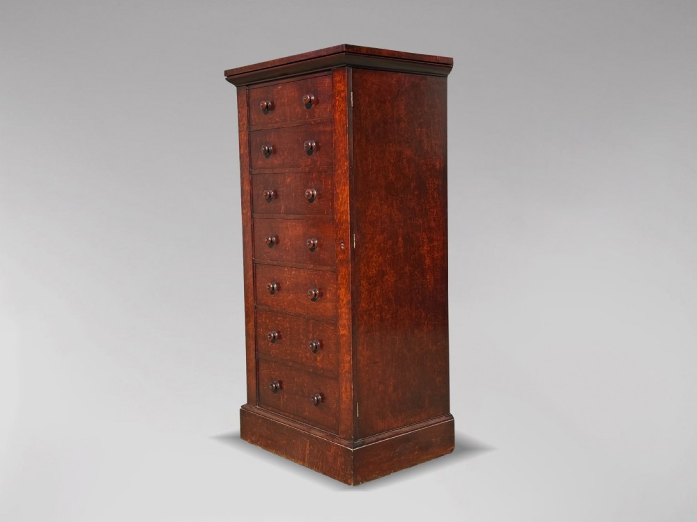 A tall 19th-century Georgian mahogany Wellington chest featuring seven graduated drawers with turned knobs and a hinged side locking flap.