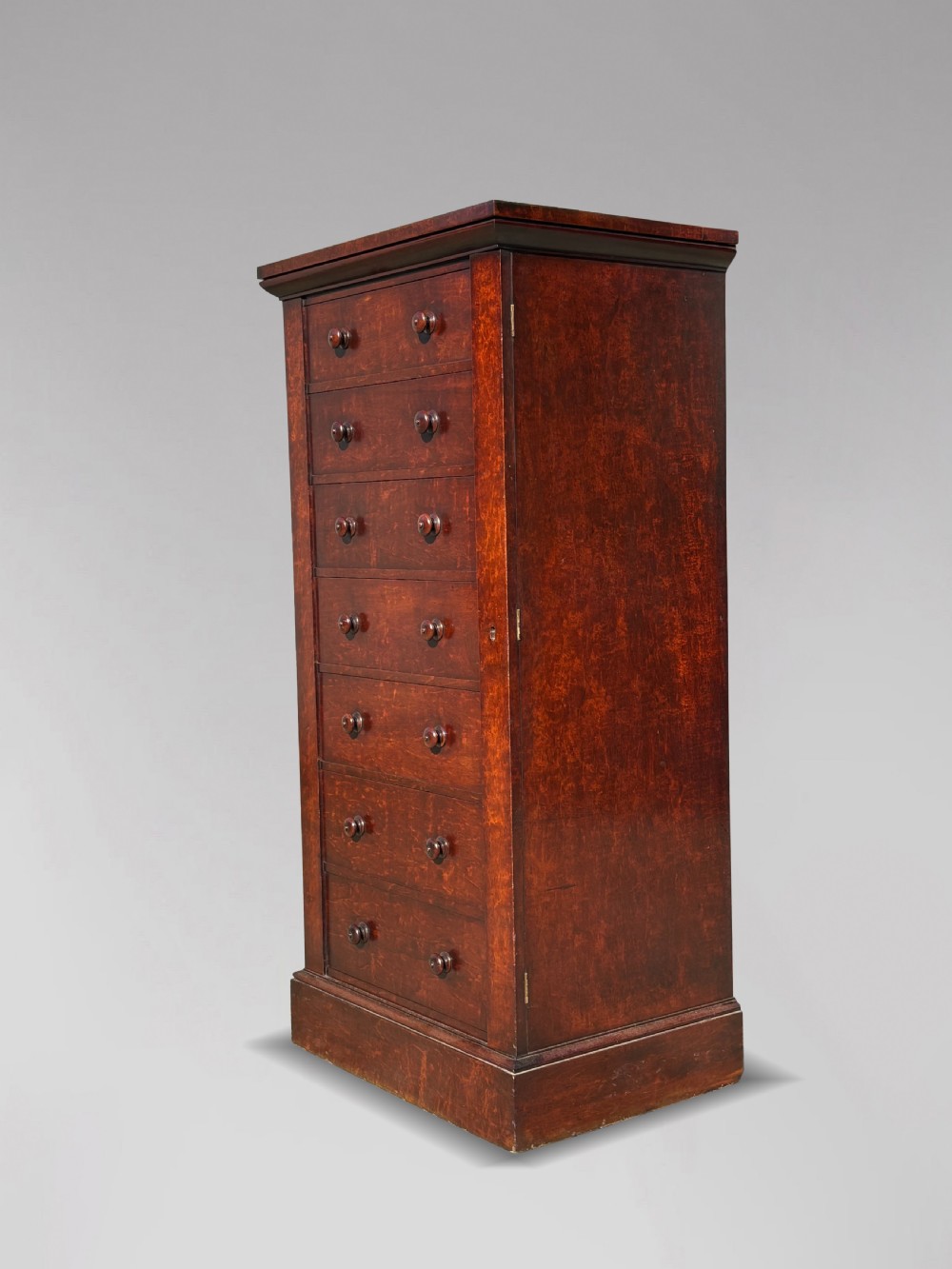 A tall 19th-century Georgian mahogany Wellington chest featuring seven graduated drawers with turned knobs and a hinged side locking flap. View II