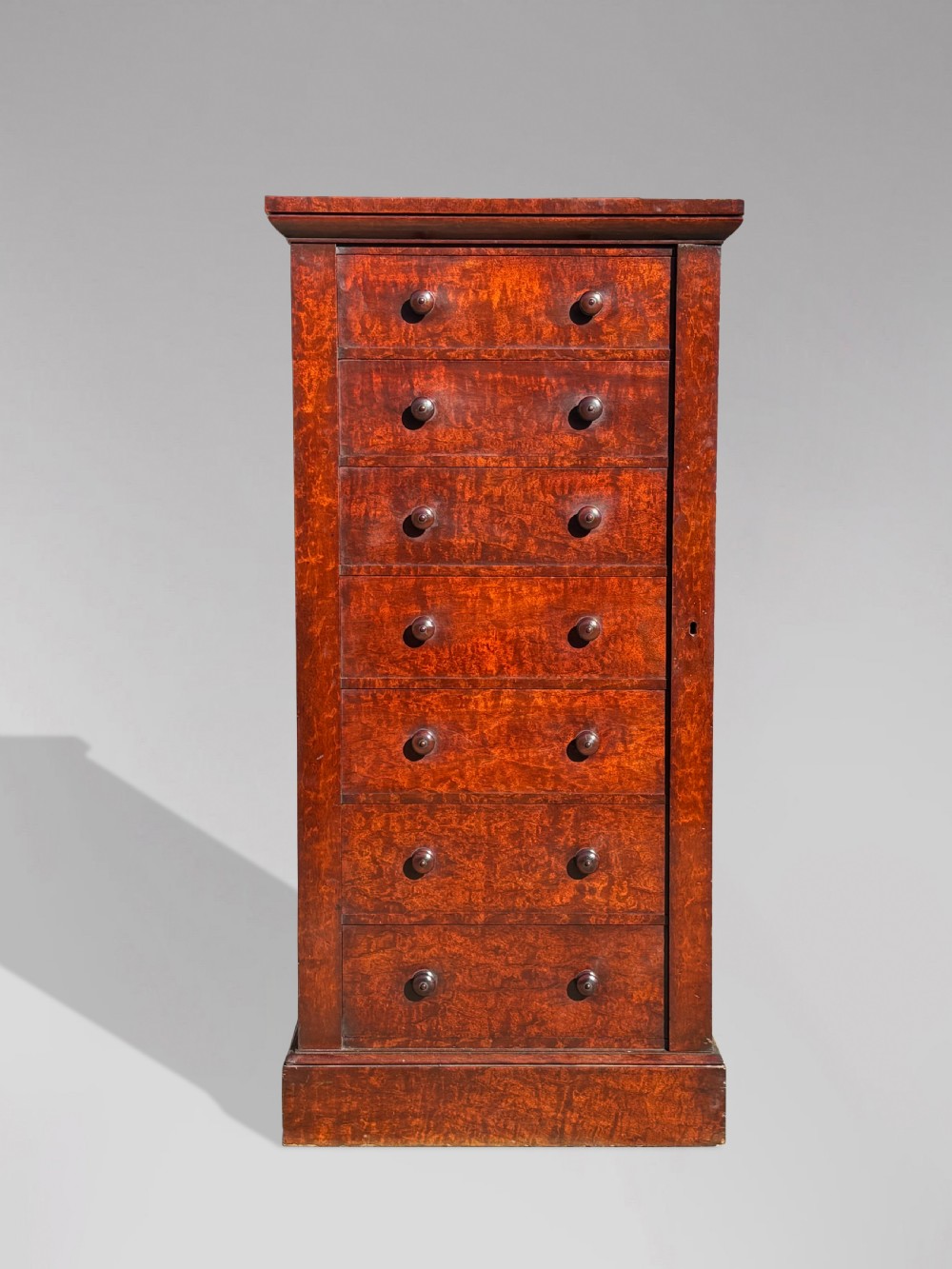 A tall 19th-century Georgian mahogany Wellington chest featuring seven graduated drawers with turned knobs and a hinged side locking flap. View V