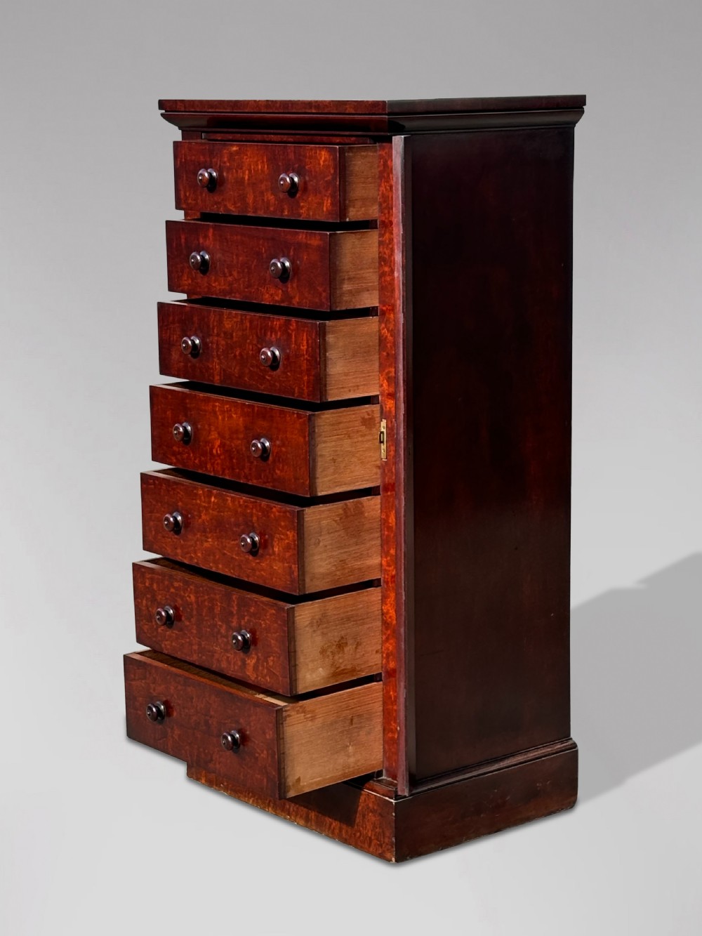 A tall 19th-century Georgian mahogany Wellington chest featuring seven graduated drawers with turned knobs and a hinged side locking flap. View VI