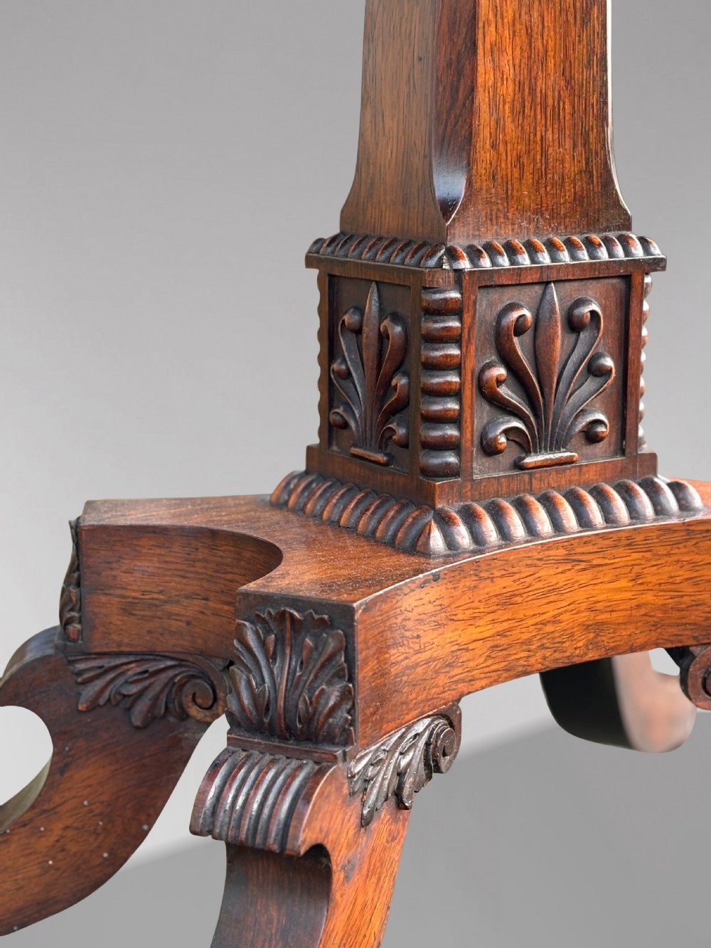 A 19th-century George IV period rosewood fold-over card table featuring a figured veneer top, carved pedestal base, and four splayed legs with brass paw castors. View V