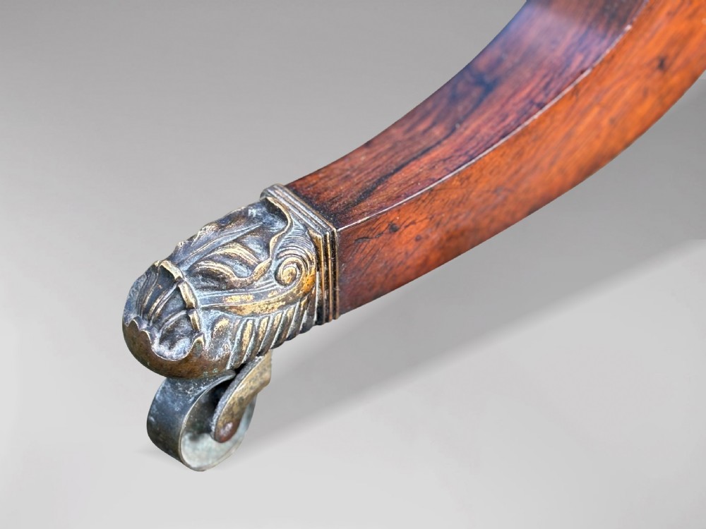 A 19th-century George IV period rosewood fold-over card table featuring a figured veneer top, carved pedestal base, and four splayed legs with brass paw castors. View VI