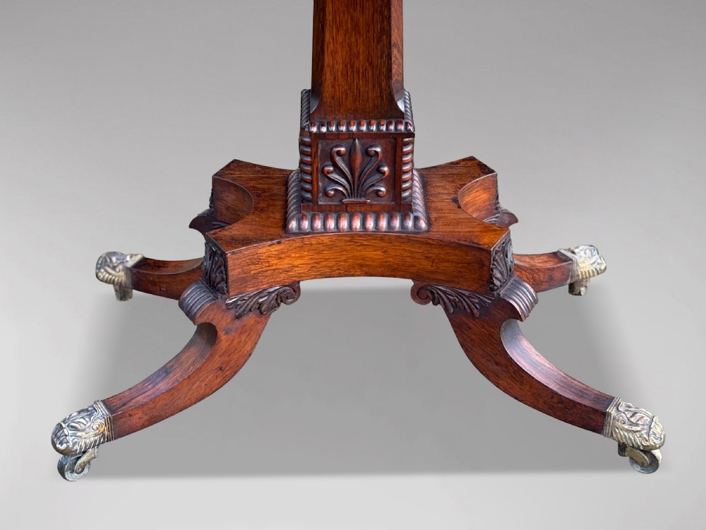 A 19th-century George IV period rosewood fold-over card table featuring a figured veneer top, carved pedestal base, and four splayed legs with brass paw castors. View VII