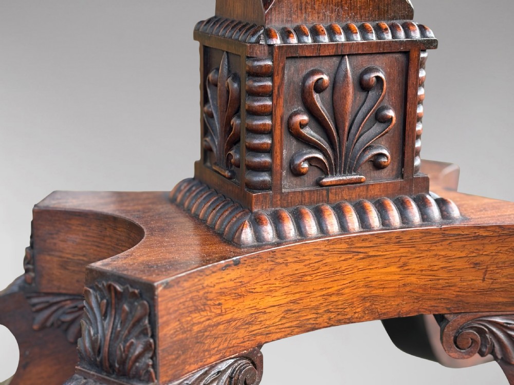 A 19th-century George IV period rosewood fold-over card table featuring a figured veneer top, carved pedestal base, and four splayed legs with brass paw castors. View XI