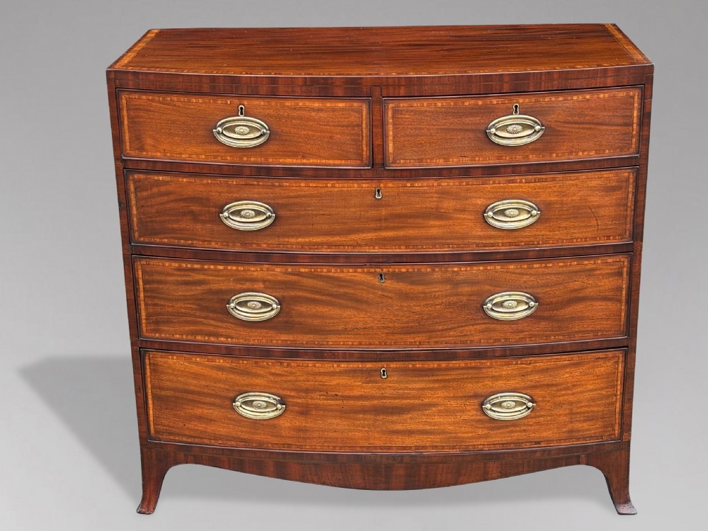 A 19th-century mahogany chest of drawers featuring two short over three long drawers, crossbanded inlay, oval brass handles, and splayed bracket feet. View II