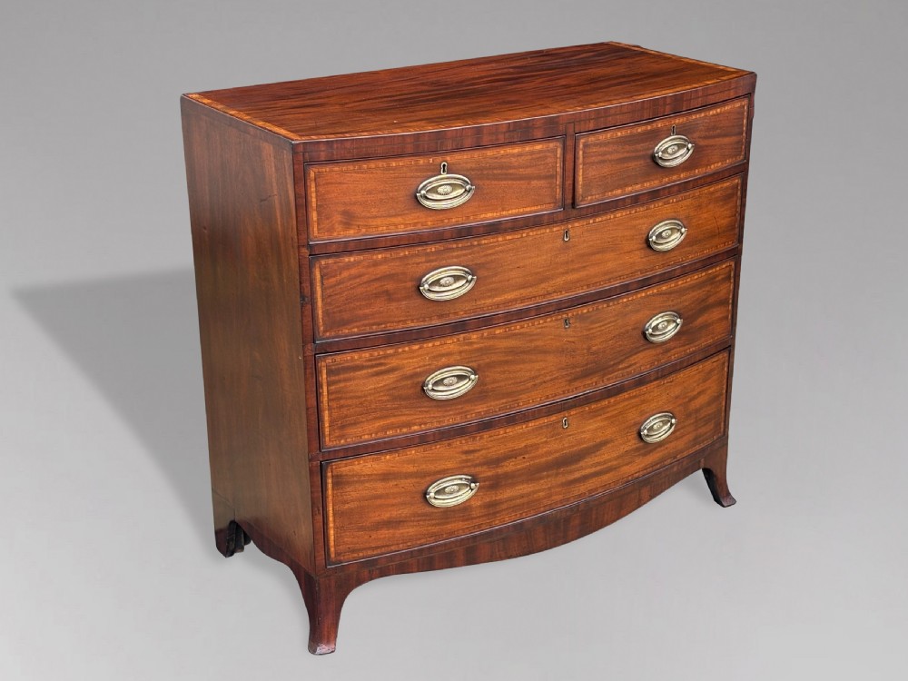 A 19th-century mahogany chest of drawers featuring two short over three long drawers, crossbanded inlay, oval brass handles, and splayed bracket feet. View III