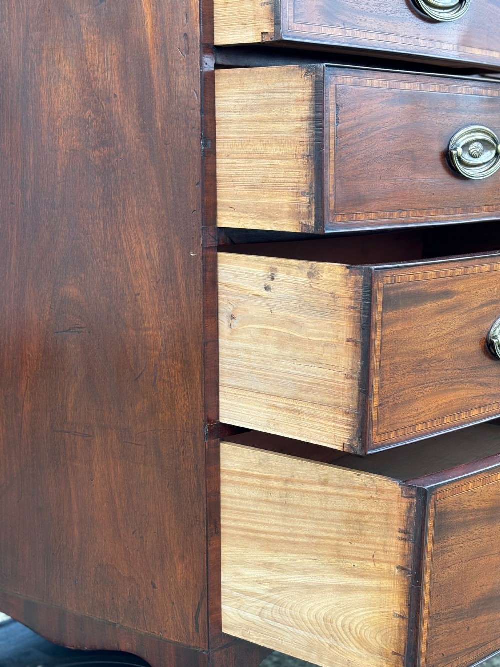A 19th-century mahogany chest of drawers featuring two short over three long drawers, crossbanded inlay, oval brass handles, and splayed bracket feet. View VII