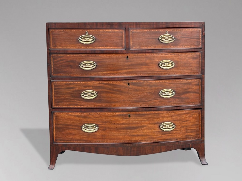 A 19th-century mahogany chest of drawers featuring two short over three long drawers, crossbanded inlay, oval brass handles, and splayed bracket feet. View IX