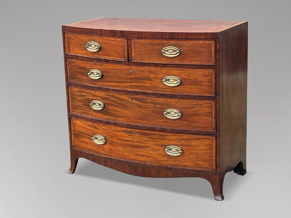 A 19th-century mahogany chest of drawers featuring two short over three long drawers, crossbanded inlay, oval brass handles, and splayed bracket feet. View XIII