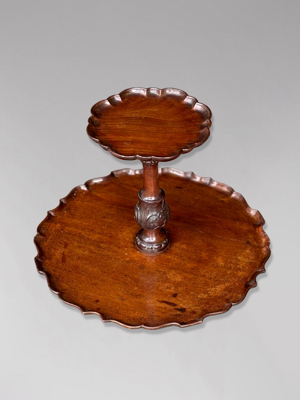 A 19th-century dark brown mahogany two-tier revolving Lazy Susan featuring scalloped piecrust rims and a turned, carved central column. View II