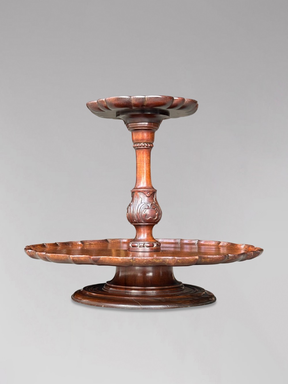 A 19th-century dark brown mahogany two-tier revolving Lazy Susan featuring scalloped piecrust rims and a turned, carved central column. View IV