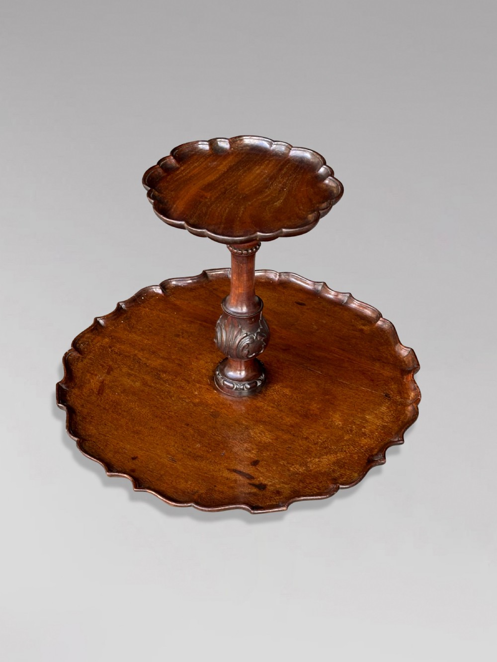 A 19th-century dark brown mahogany two-tier revolving Lazy Susan featuring scalloped piecrust rims and a turned, carved central column. View VIII