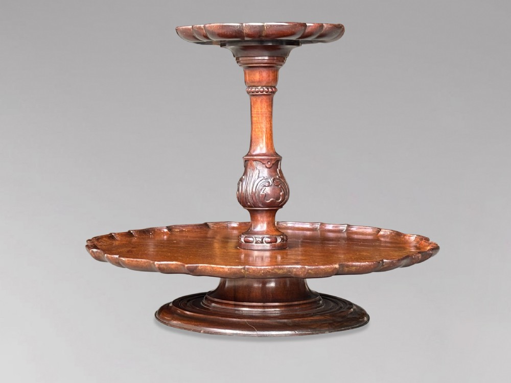 A 19th-century dark brown mahogany two-tier revolving Lazy Susan featuring scalloped piecrust rims and a turned, carved central column. View IX