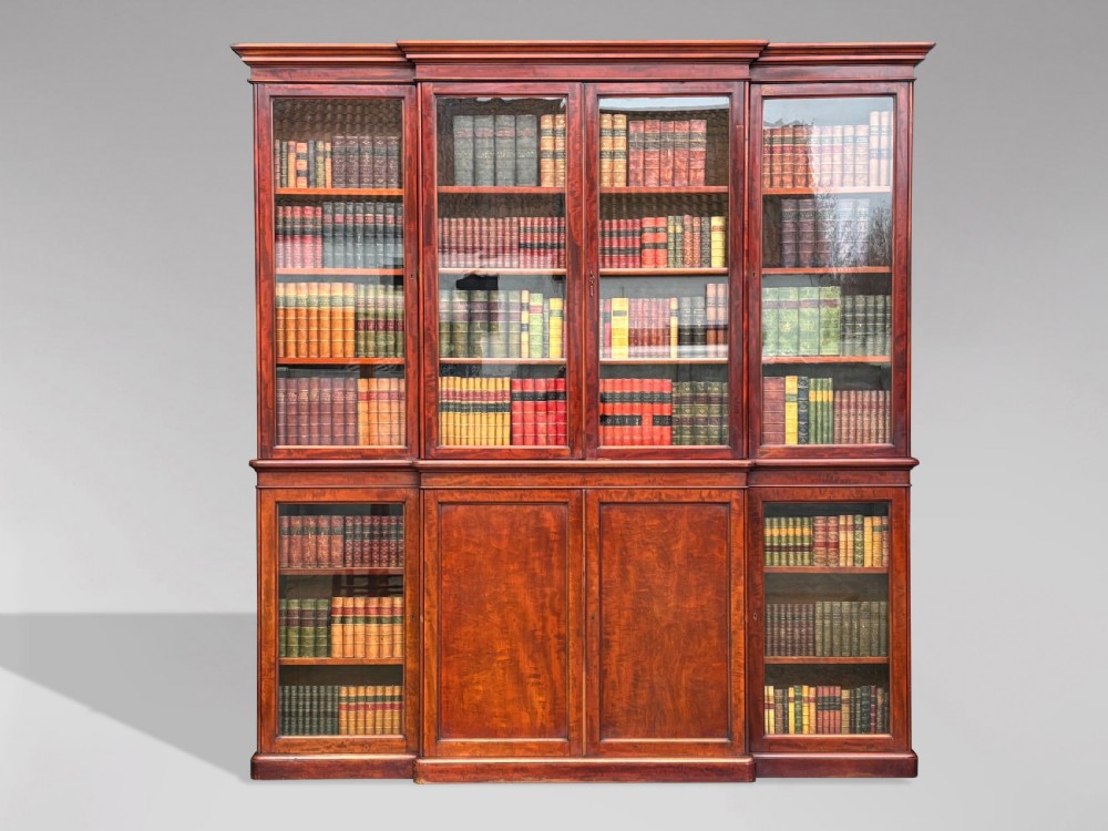 A large mid-nineteenth-century mahogany breakfront library bookcase featuring glazed upper doors, panelled lower cupboard doors, and a stepped moulded cornice.