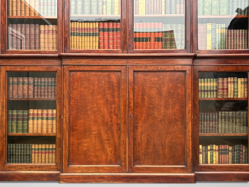 A large mid-nineteenth-century mahogany breakfront library bookcase featuring glazed upper doors, panelled lower cupboard doors, and a stepped moulded cornice. View V