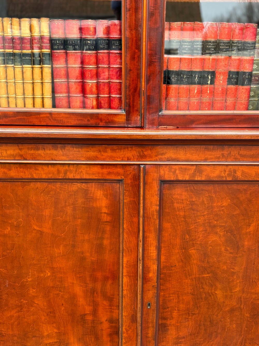 A large mid-nineteenth-century mahogany breakfront library bookcase featuring glazed upper doors, panelled lower cupboard doors, and a stepped moulded cornice. View VI