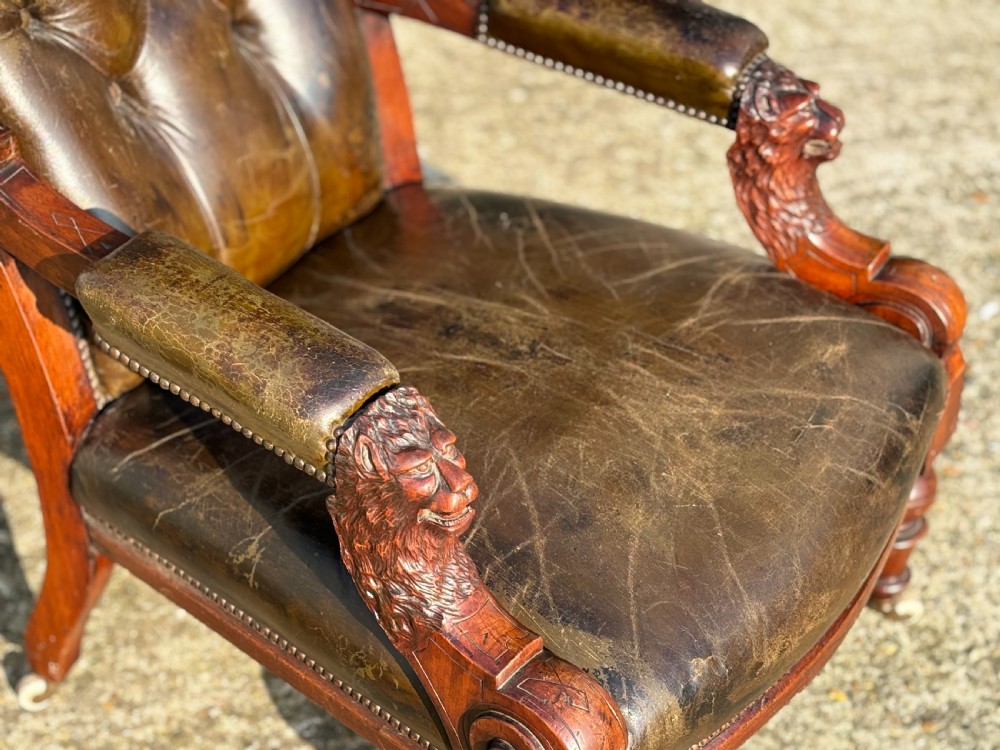 A nineteenth-century carved walnut library armchair with button-tufted dark green leather upholstery, carved lion-head armrests, and turned legs with castors. View VII