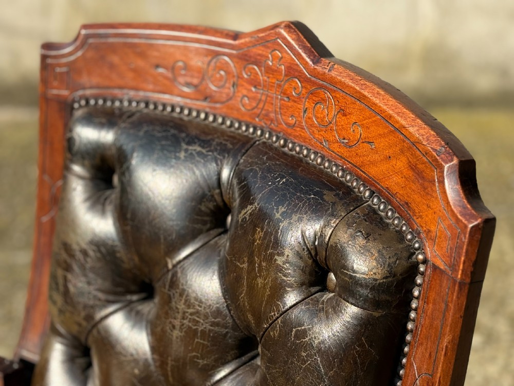 A nineteenth-century carved walnut library armchair with button-tufted dark green leather upholstery, carved lion-head armrests, and turned legs with castors. View VIII