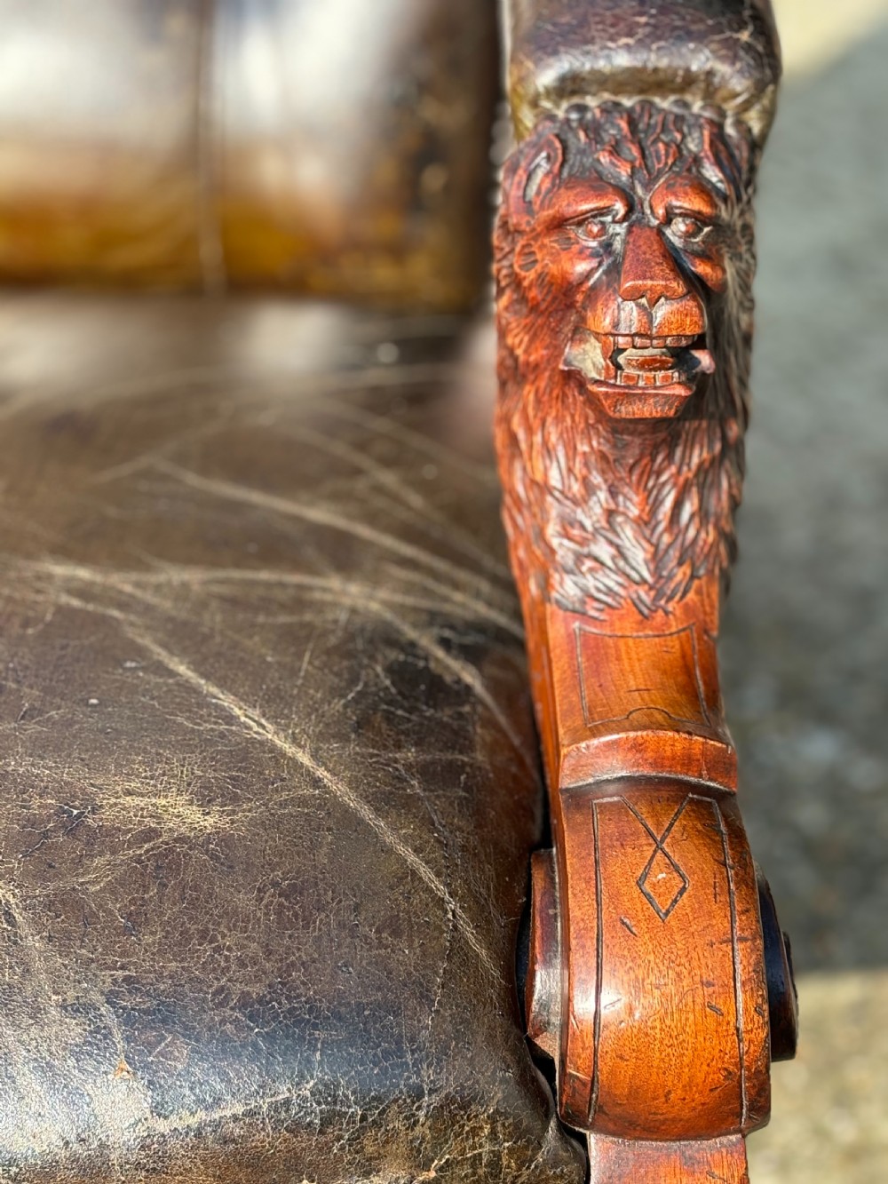 A nineteenth-century carved walnut library armchair with button-tufted dark green leather upholstery, carved lion-head armrests, and turned legs with castors. View IX
