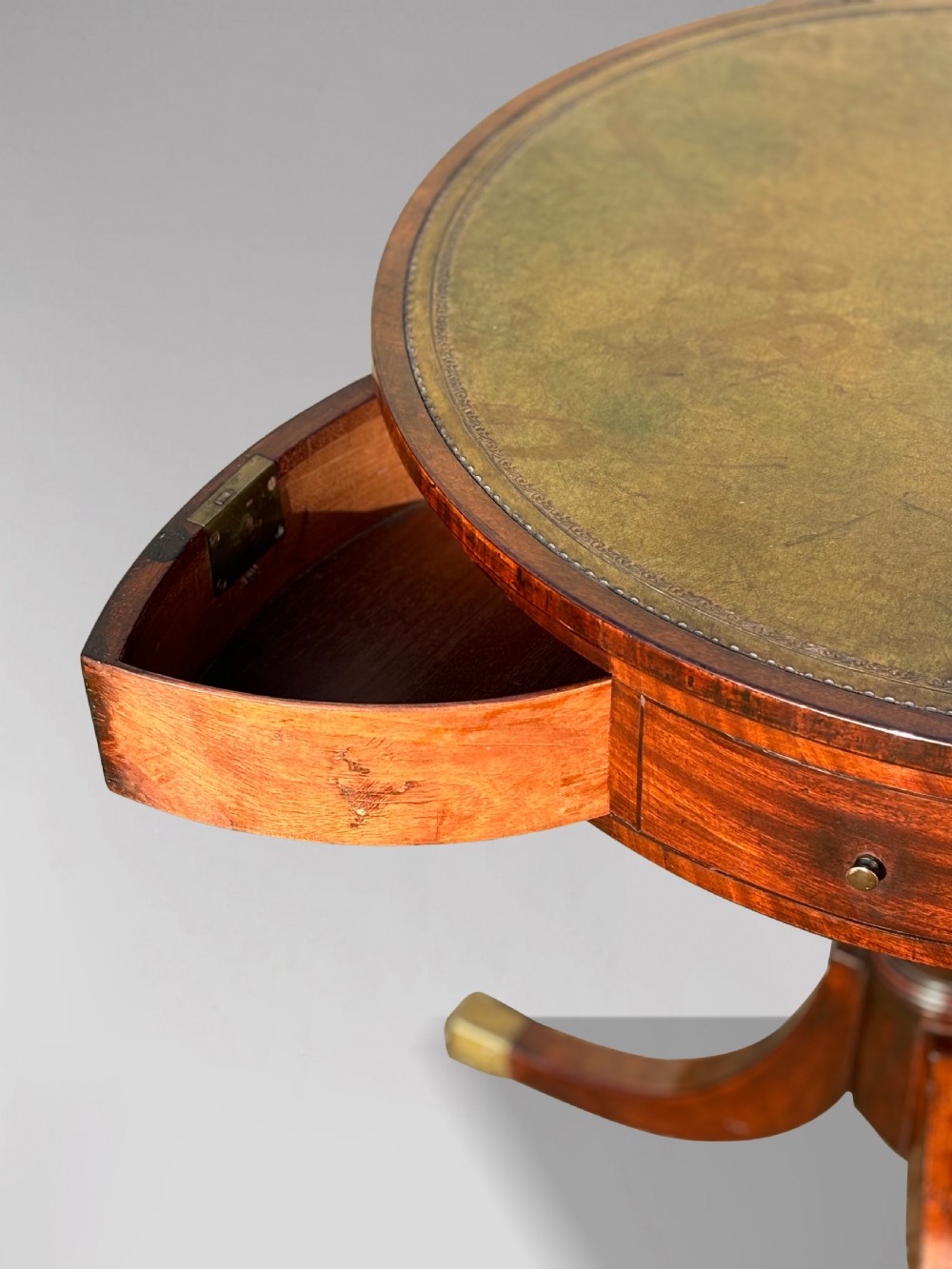 An 18th-century George III mahogany drum table with a circular green leather top, frieze drawers, turned pedestal, and splayed legs with brass castors. View II