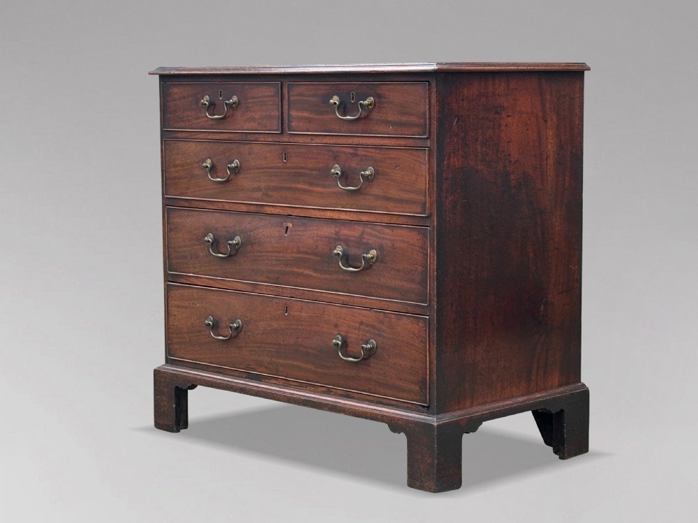 An 18th-century George III mahogany chest of drawers featuring two short over three long graduated drawers with brass swan-neck handles and bracket feet.