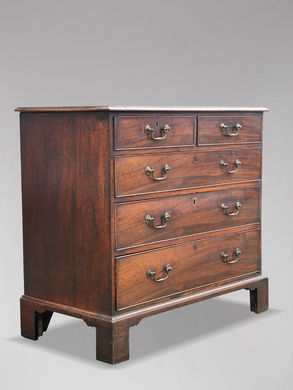 An 18th-century George III mahogany chest of drawers featuring two short over three long graduated drawers with brass swan-neck handles and bracket feet. View IX