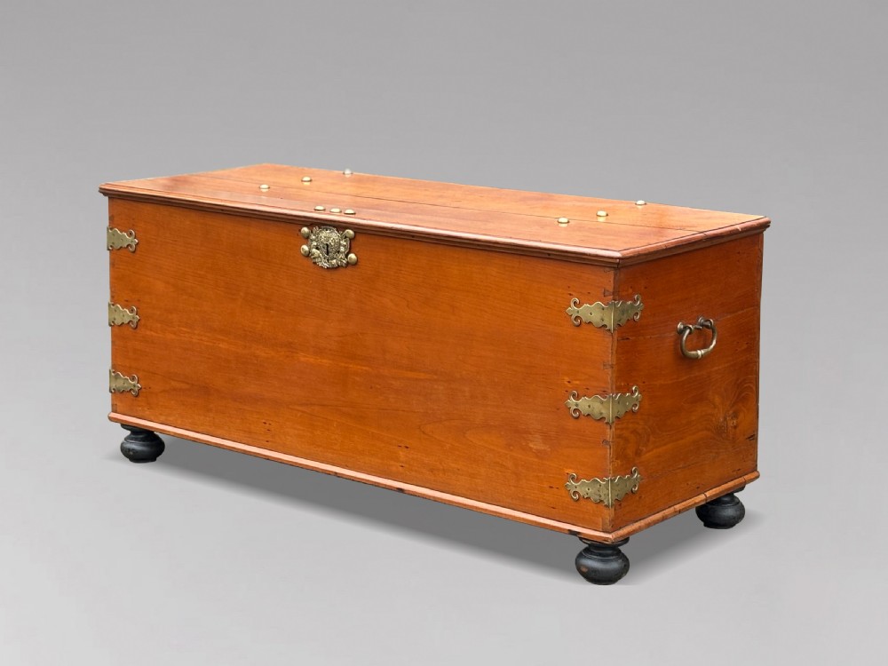 An 18th-century warm brown walnut colonial chest featuring brass corner brackets, a central decorative brass escutcheon, lid studs, and dark turned bun feet. View VIII