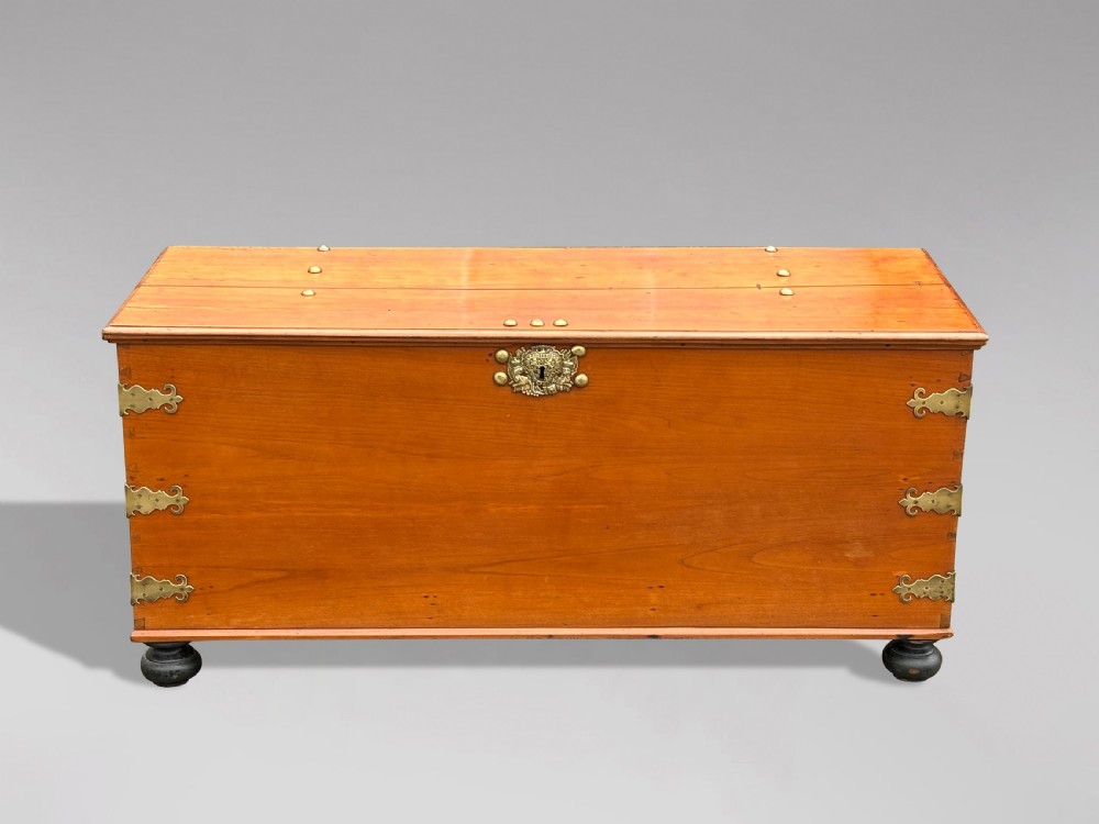 An 18th-century warm brown walnut colonial chest featuring brass corner brackets, a central decorative brass escutcheon, lid studs, and dark turned bun feet. View IX