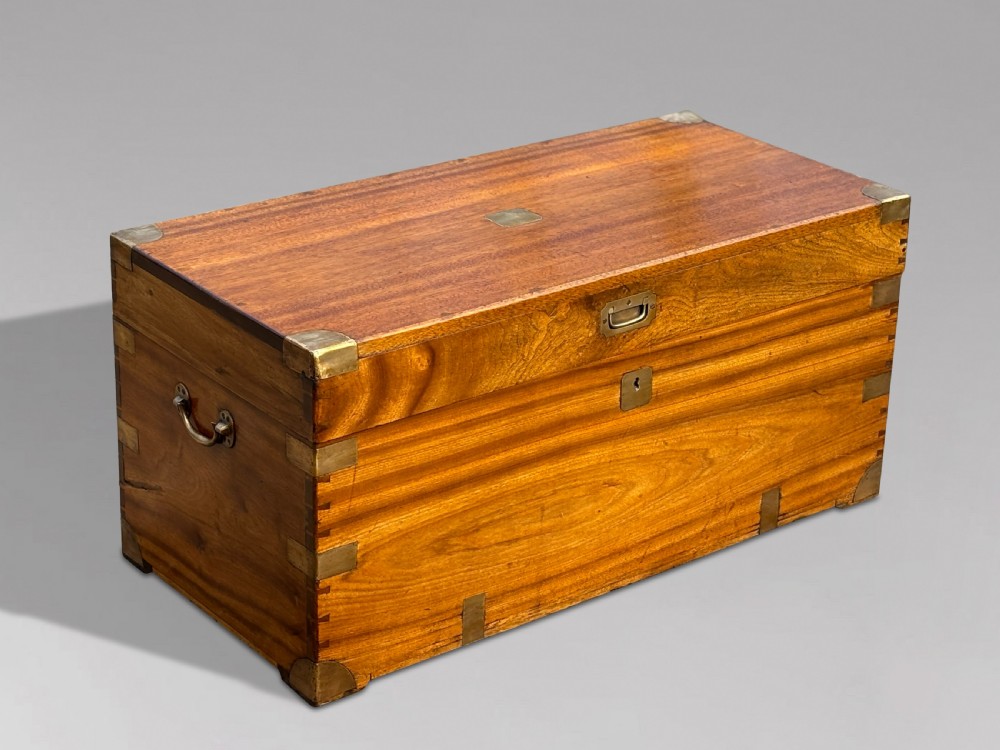 A rectangular 19th-century camphor wood campaign trunk featuring flush brass corner brackets, recessed side handles, and a central brass lock plate.