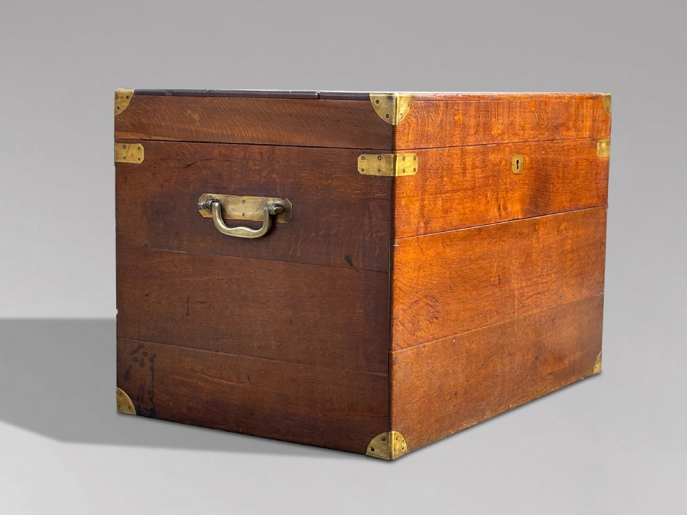 A large rectangular 19th-century oak travelling trunk featuring brass corner mounts, drop side handles, and an inlaid lid cartouche. View IV