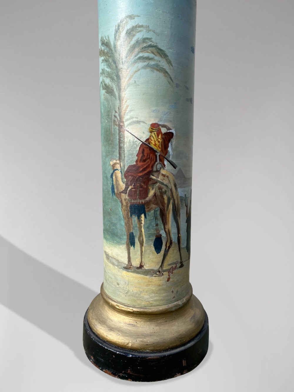 A pair of 19th-century French hand-painted cylindrical wooden columns featuring narrative desert and riverbank scenes above turned gilded bases. View III