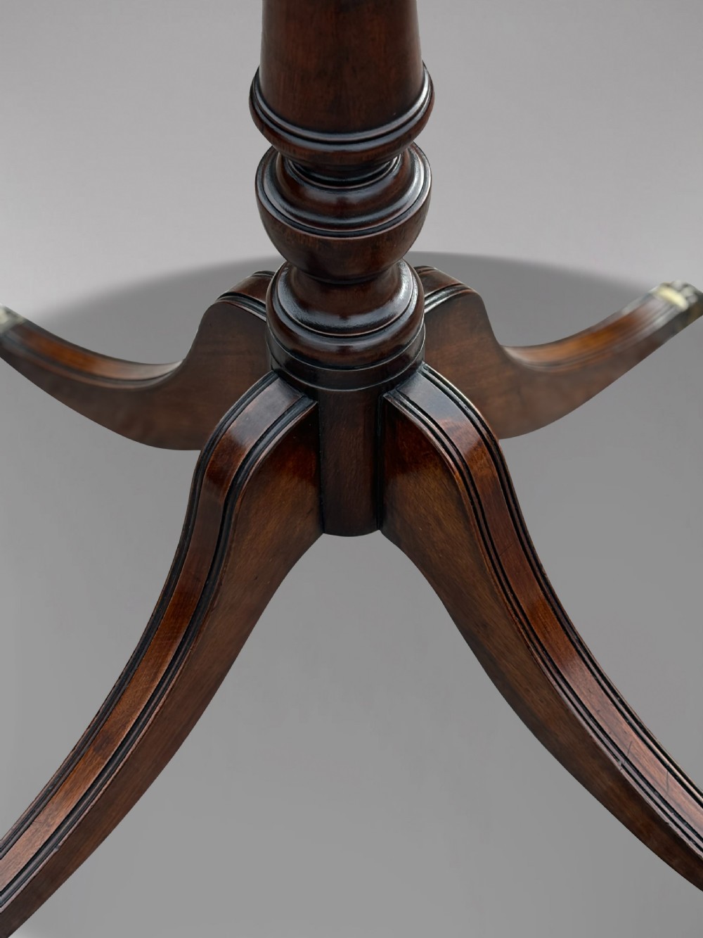 A 19th-century circular mahogany drum table featuring a red leather inlaid top, brass lion mask handles on perimeter drawers, and a pedestal base on splayed legs with brass paw castors. View VII
